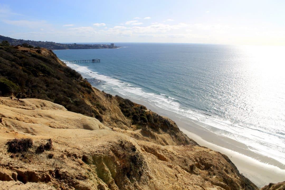 A view from sandstone cliffs that overlook a beach.