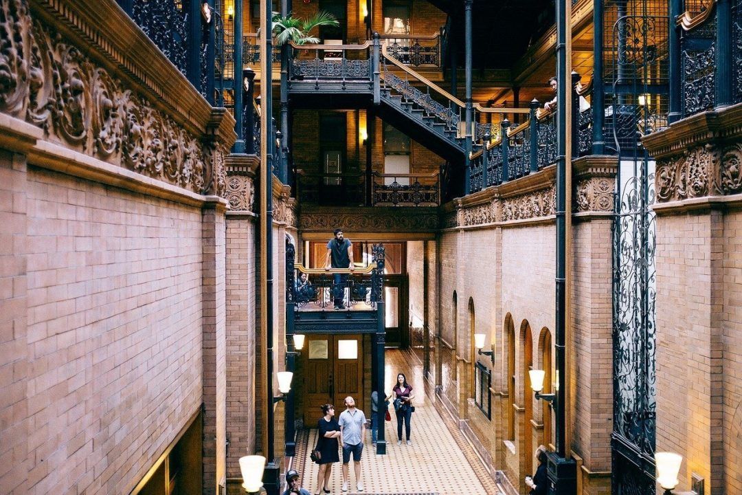 People admiring the ornate architecture in the lobby atrium of a building.
