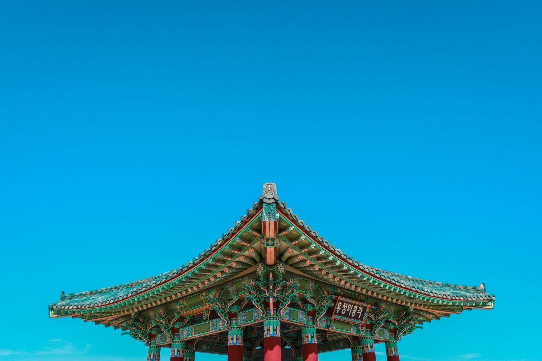 The top of an ornate pagoda against a bright blue sky.
