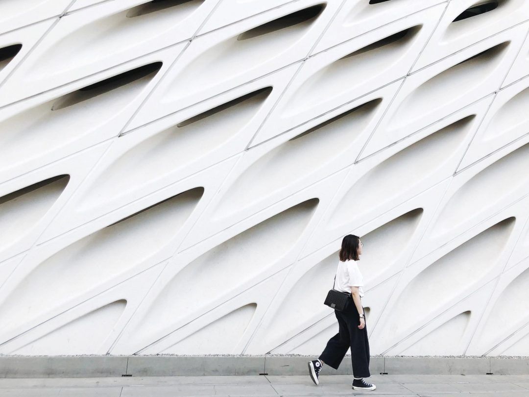 A woman walking past a textured white wall at The Broad Museum.