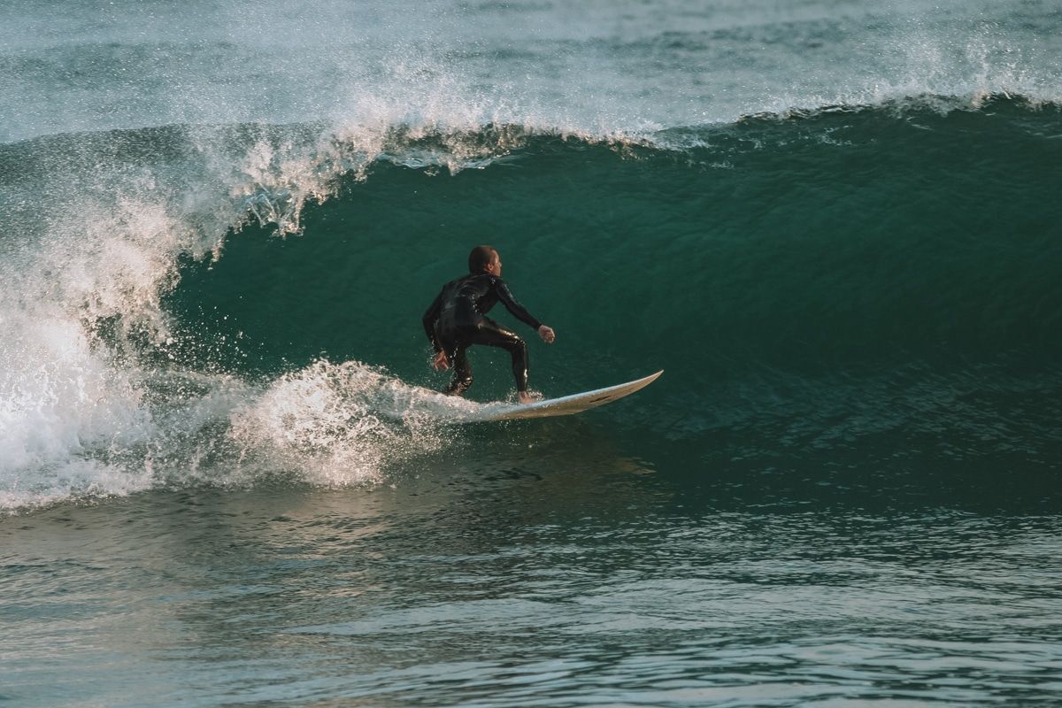 A person in a black wetsuit surfs a wave.