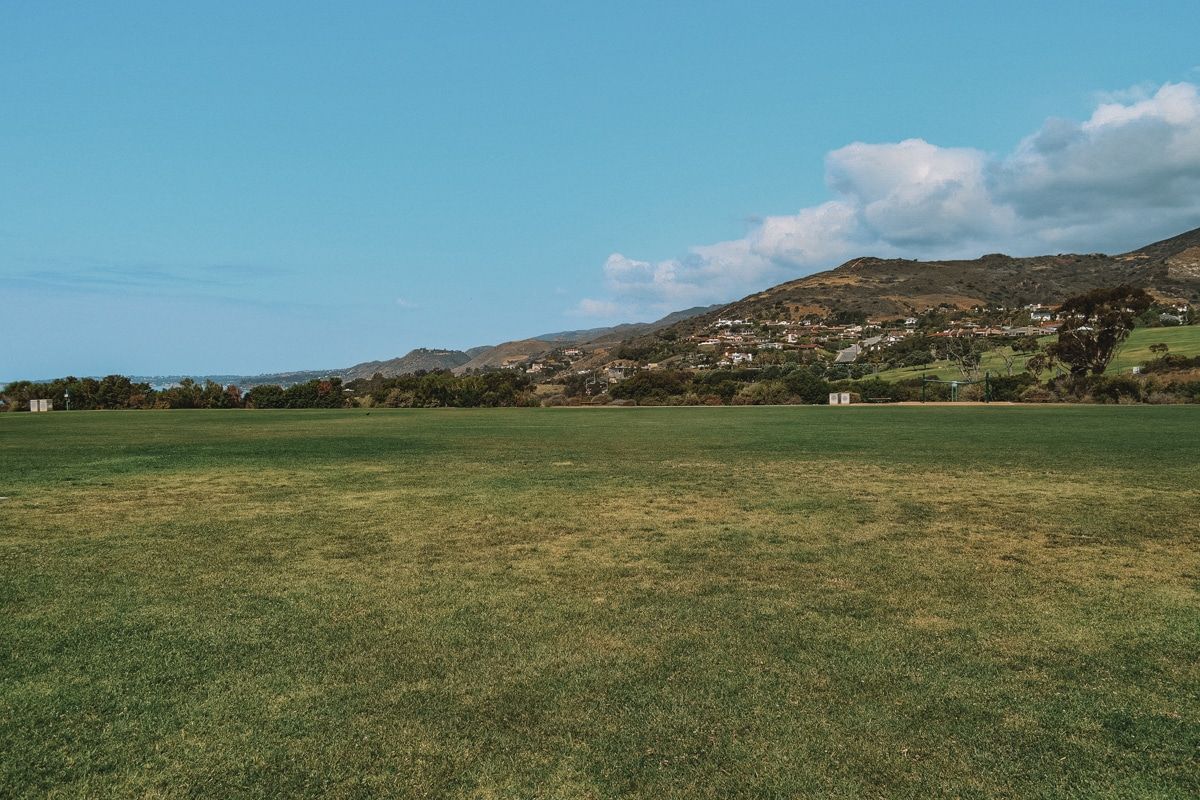 The wide, empty lawn at Malibu Bluffs Park, with some hills and a bright blue sky beyond.