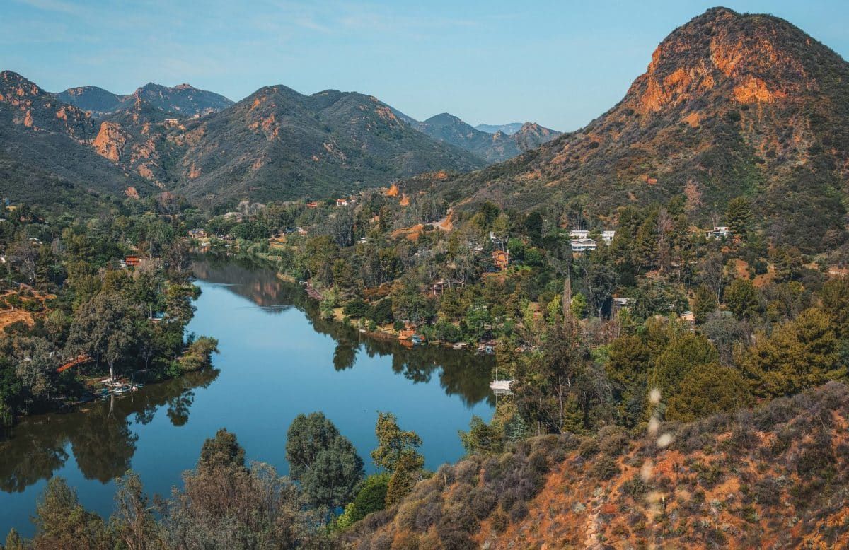 Beautiful view of Malibu lake surrounded by mountains dotted by houses and trees in Malibu Creek State Park, California.