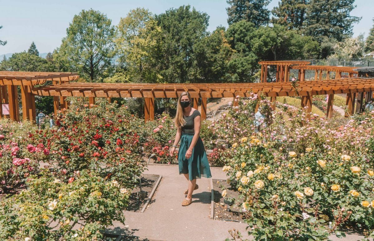 A woman in a rose garden wearing Birdies shoes on a hot summer day.