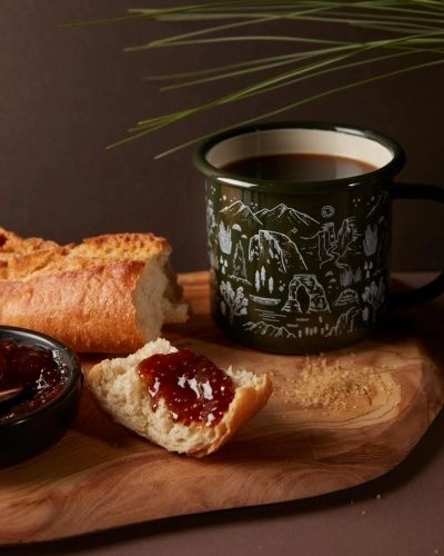 The National Park Mug filled with coffee and on a platter with bread and jam. 