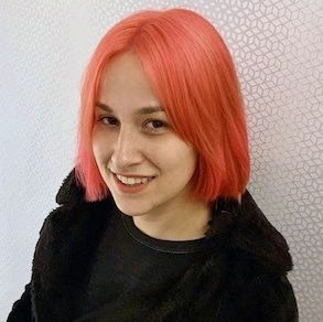 Elina Ansary with pink shoulder-length hair, wearing a black jacket and shirt.