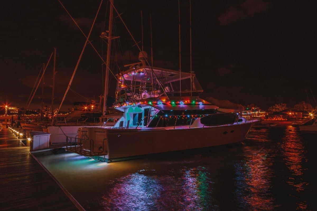 A nighttime scene of a yacht illuminated with Christmas lights at a dock during the Newport Beach Christmas-lighted boat parade.