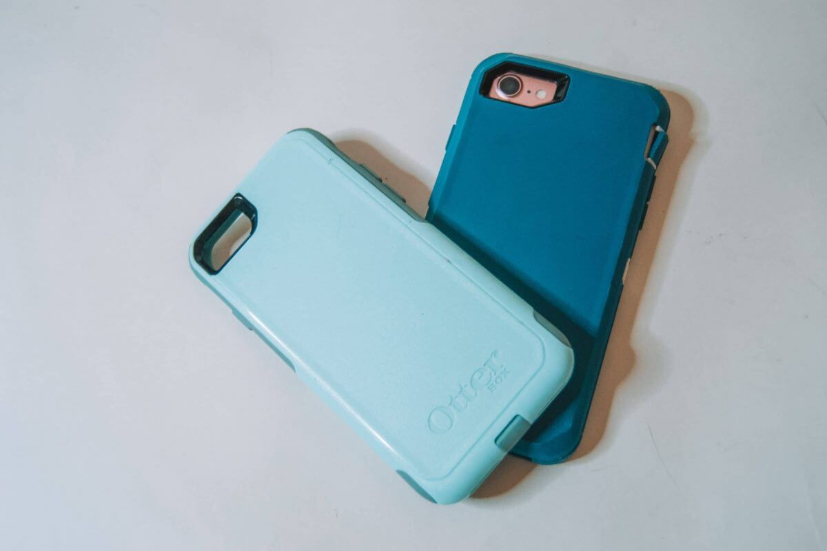 Two phone cases placed on top of each other, comparing the Otterbox Defender vs Commuter series, against a white background.