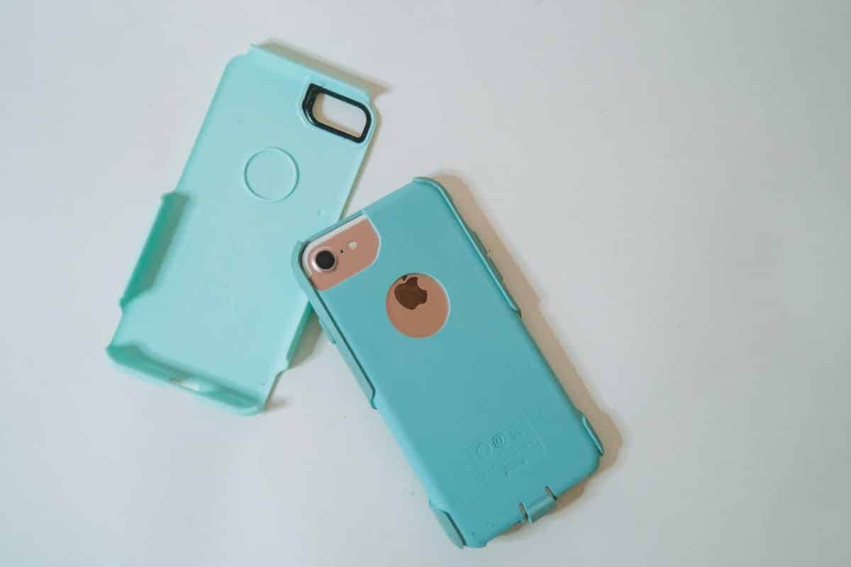 A teal Otterbox Commuter phone case separated into two parts, sitting on a white background.