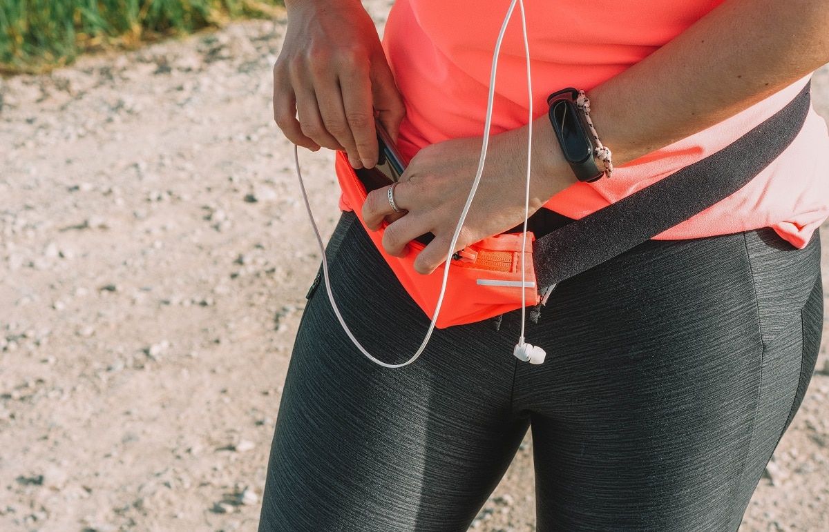 athlete woman putting phone inside fanny pack