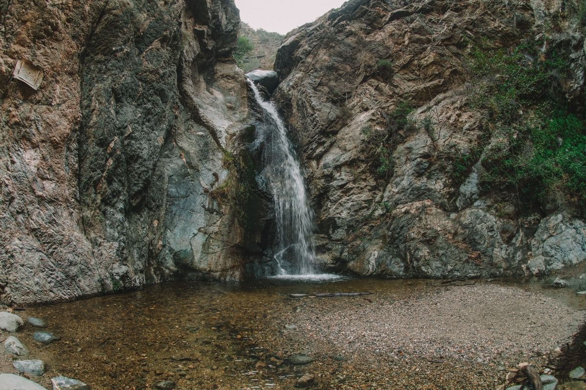 Eaton Canyon Falls, a small waterfall pouring through rocks into a shallow lagoon.