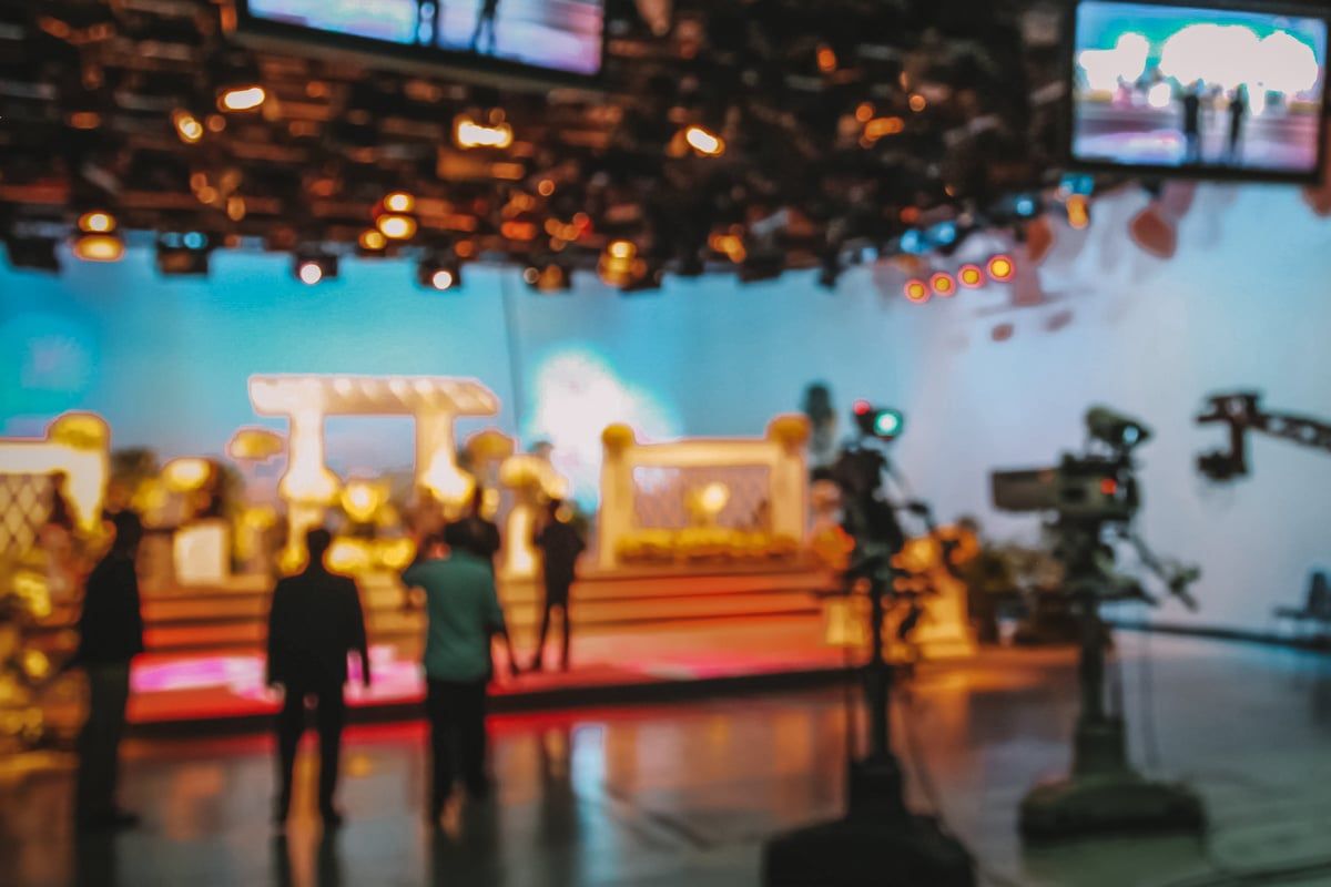 Blurry view of people working on a lit soundstage during a live taping of a tv show.
