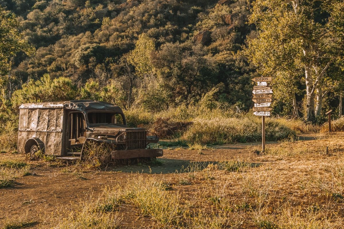 An old fashioned, abandoned truck next to a signpost at Malibu Creek State Park.
