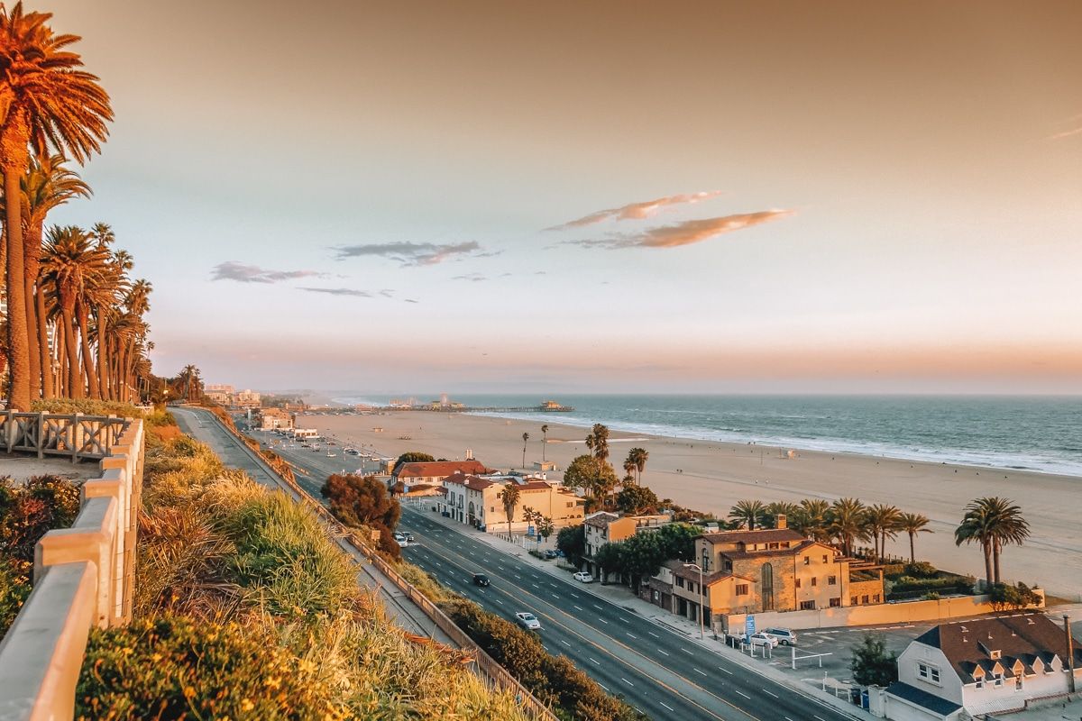 A view from above showing the Pacific Coast Highway running alongside the beach at sunset.