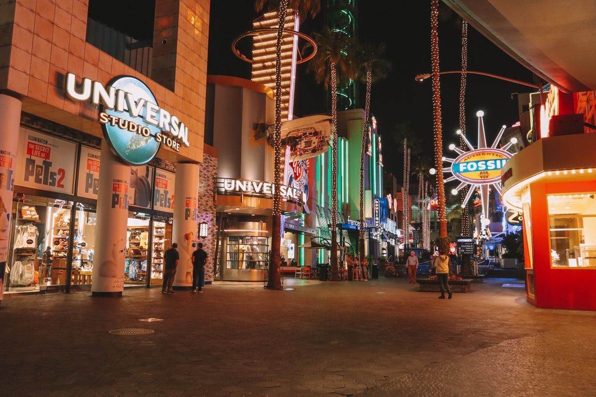 People taking the in the bright lights of the Universal Citywalk at night.