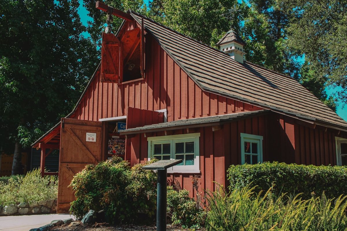 Walt Disney's carolwood barn, a small, red, A-frame barn surrounded by treees.