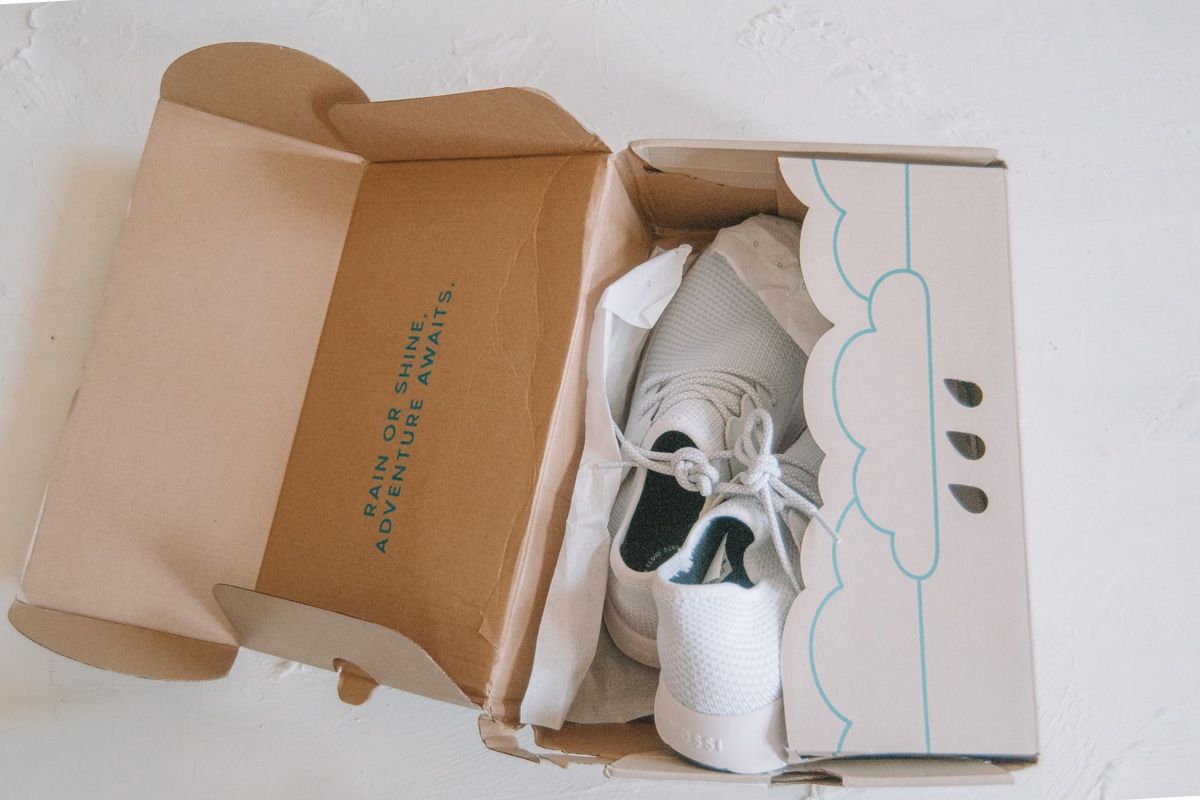 A pair of white Vessi Shoes inside an open shoebox on a white background.