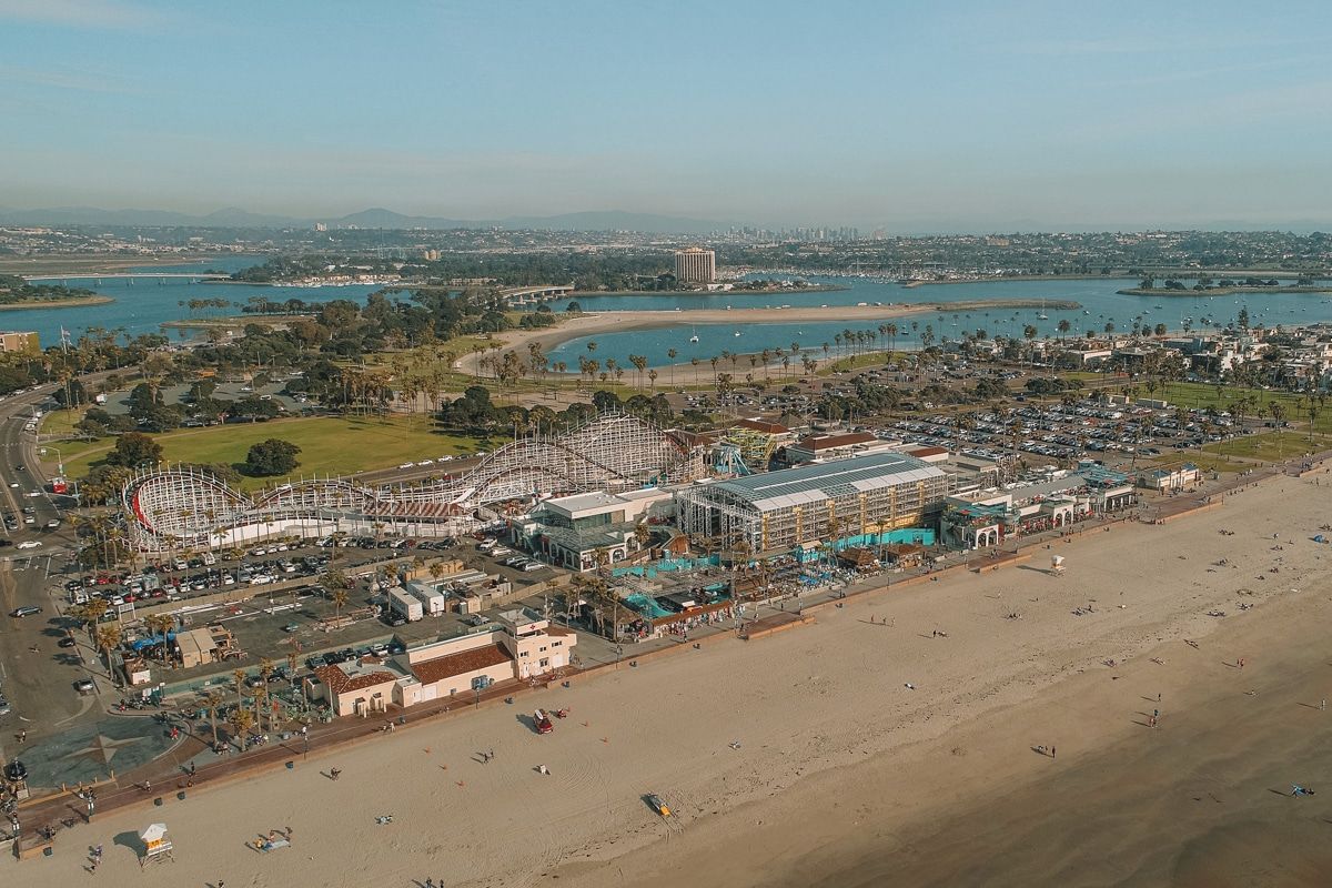 Aerial view of Belmont Park showing an amusement park with a roller coaster beside a sandy beach.