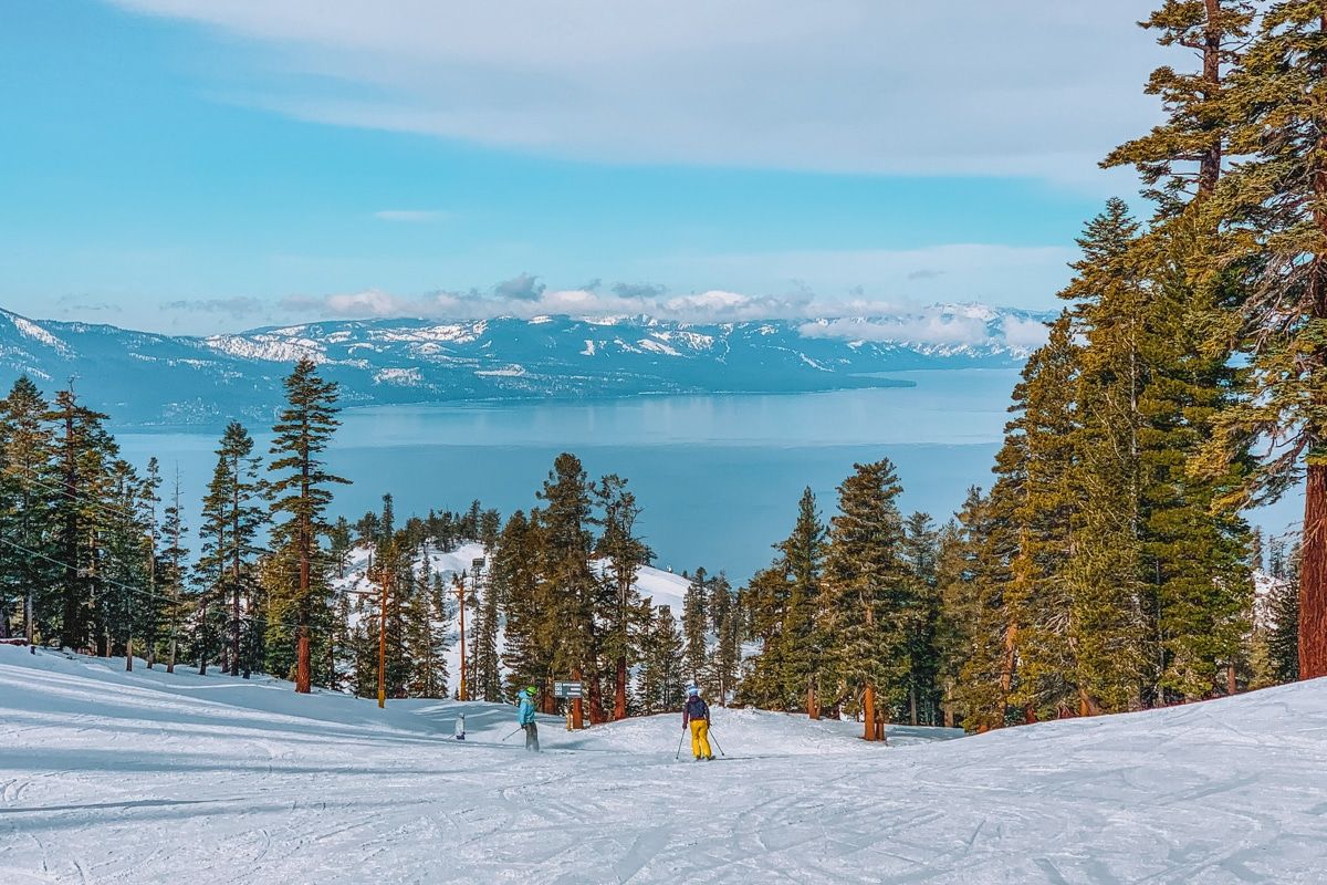 Skiers skiing down a mountain that looks over Lake Tahoe at Heavenly Mountain Resort.