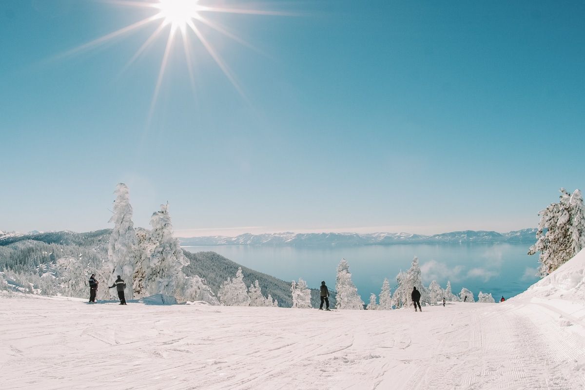 A few people staring at the lake and enjoying a winter wonderland at Lake Tahoe on a sunny day.