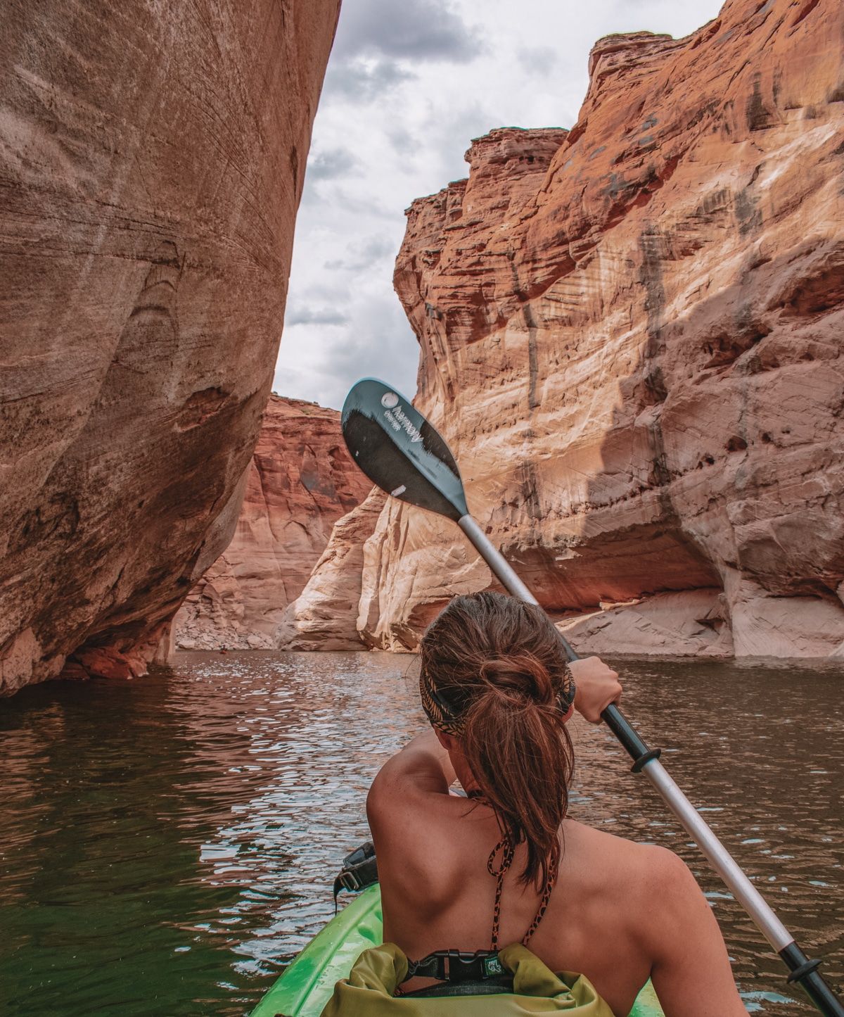 Taken from behind as a woman kayaks through narrow canyons.