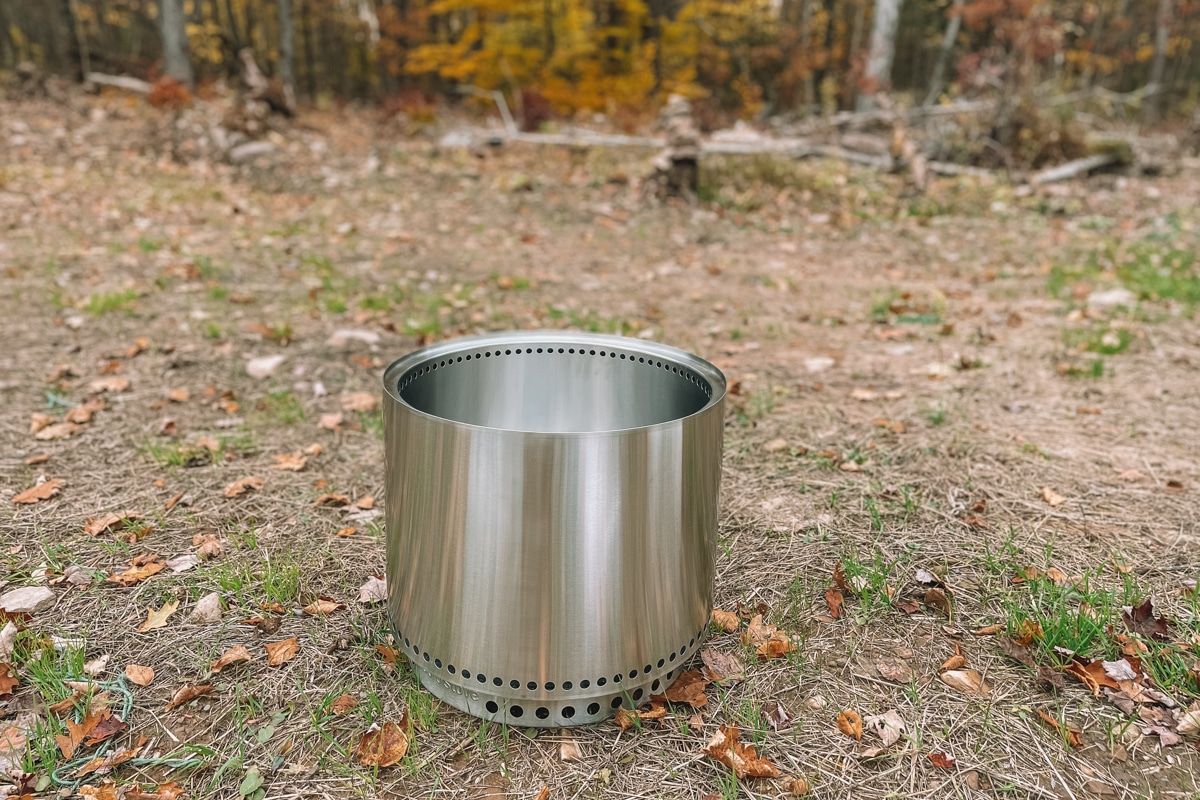 A new Solo Stove sitting on the ground outdoors with fall leaves scattered around.