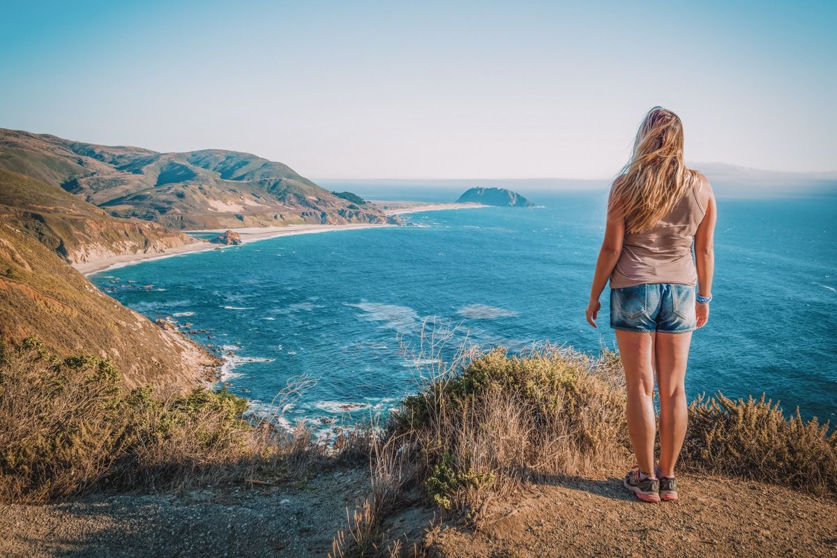A picture of a girl on Highway 1 looking out over the beautiful Big Sur coastline.