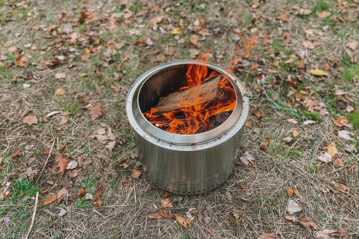 A fire burning inside a Solo Stove sitting on the ground outdoors.
