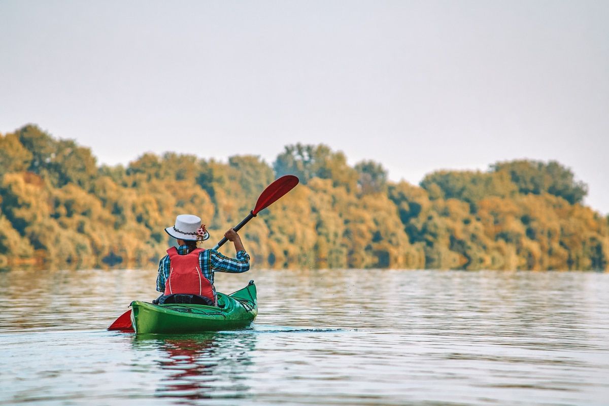 A woman paddling a green kayak on a river