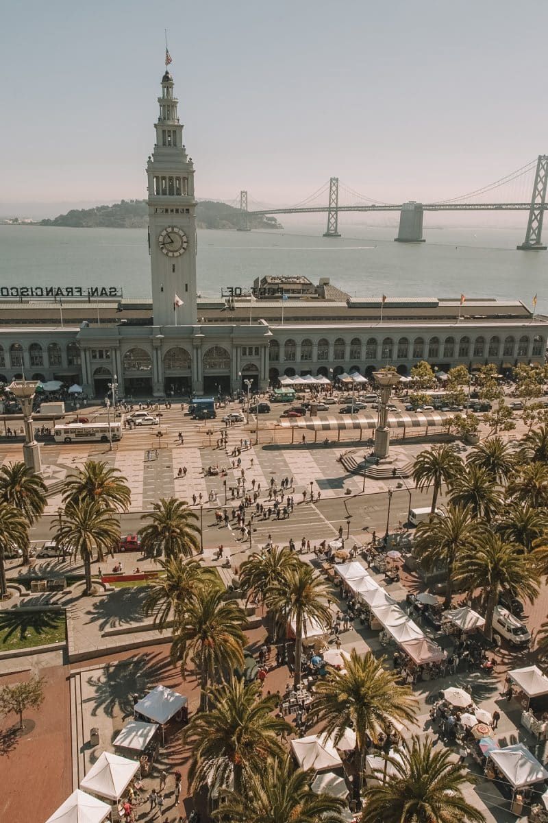 Bird's eye view of the Ferry Building in San Francisco with the SF Bay and the Bay Bridge in the background.