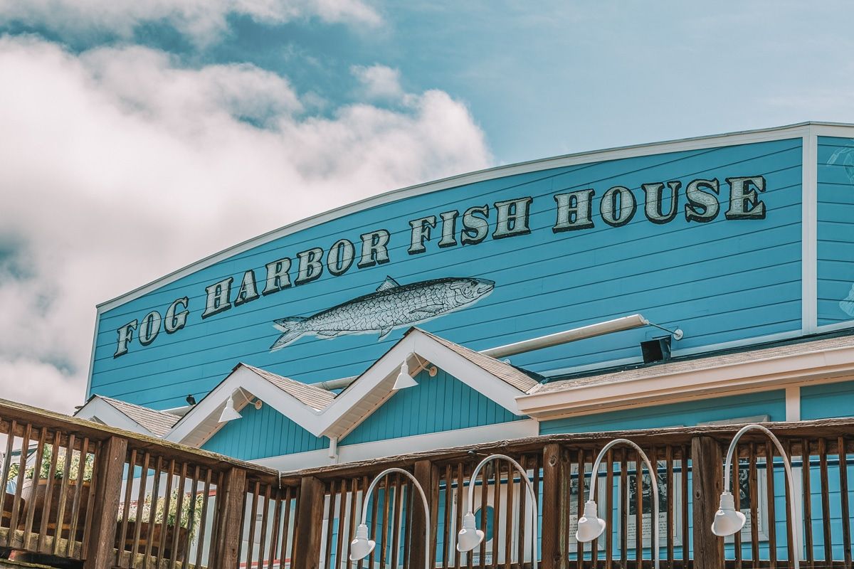 The blue-painted front facade of Fog Harbor Fish House, a wooden-sided building.