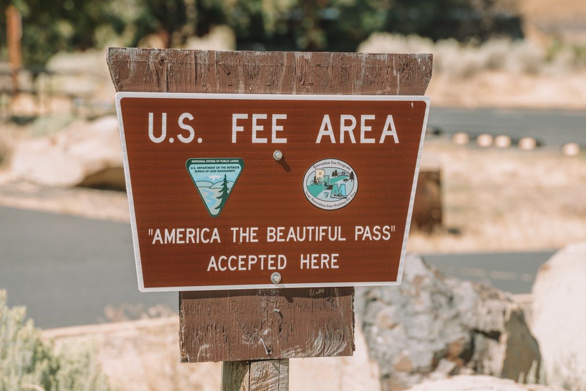 A close up of a sign that says US Fee Area-America the Beautiful Pass Accepted Here.