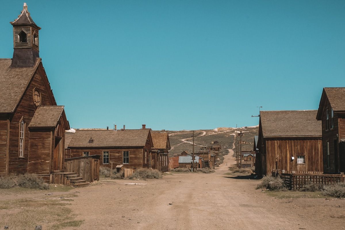 A dirt road lined by abandoned wooden buildings in Bodie Ghost Town, California.