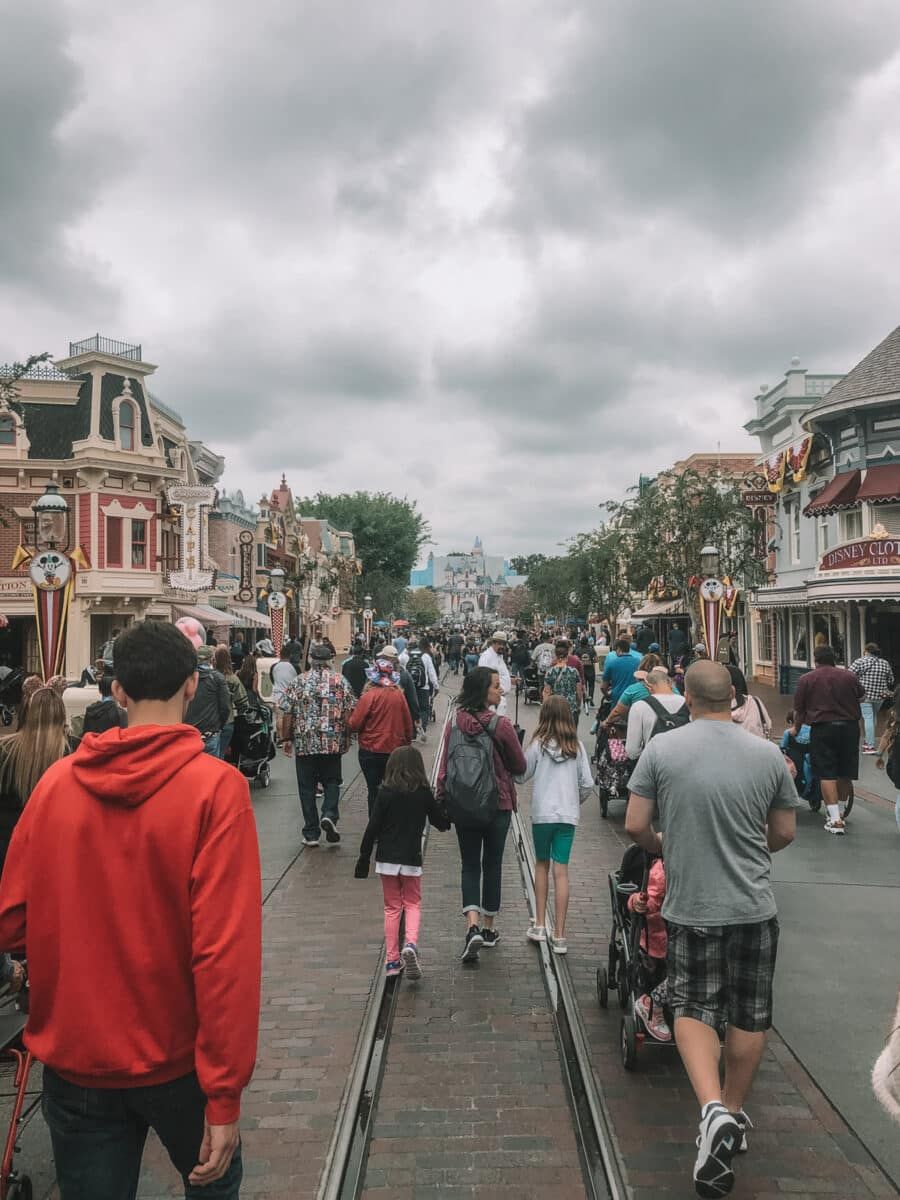 People, who may have used the Disneyland Magic Key Pass, walking through Disneyland under an overcast sky.