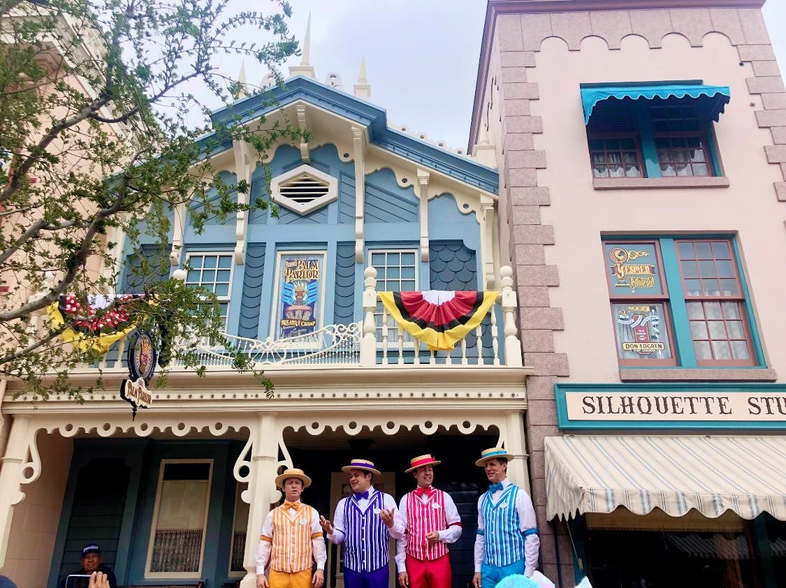 A colorfully-dressed barbershop quartet standing outside on Disneyland's Main Street.