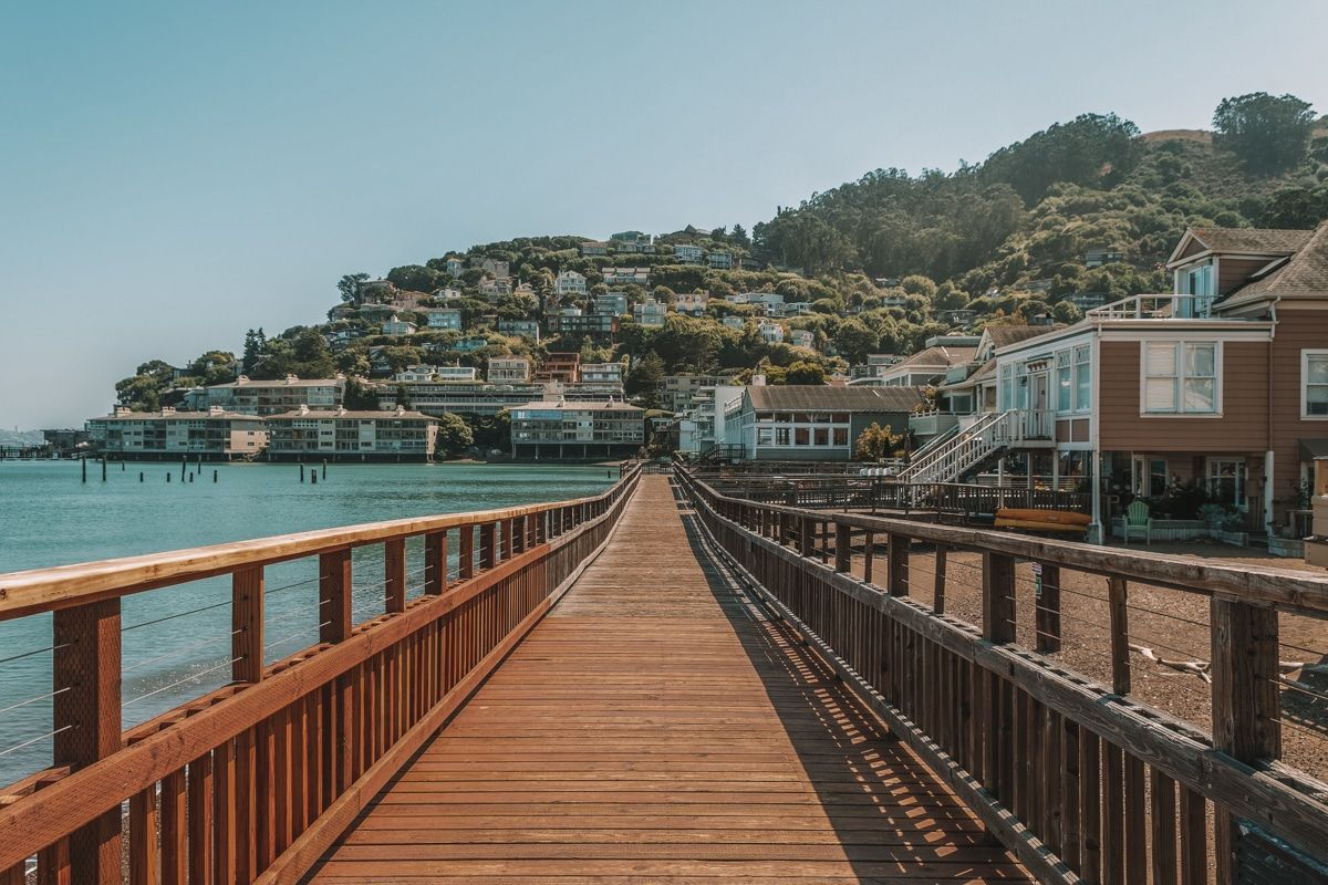 A wooden walkway running alongside the water, leading towards Sausalito.