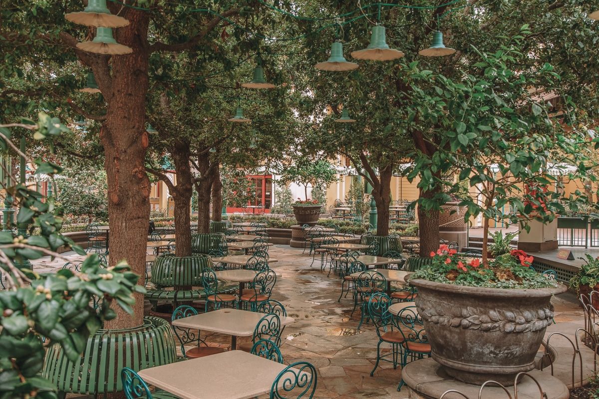 An outdoor eating area in Disneyland with trees forming a canopy of leaves overhead.