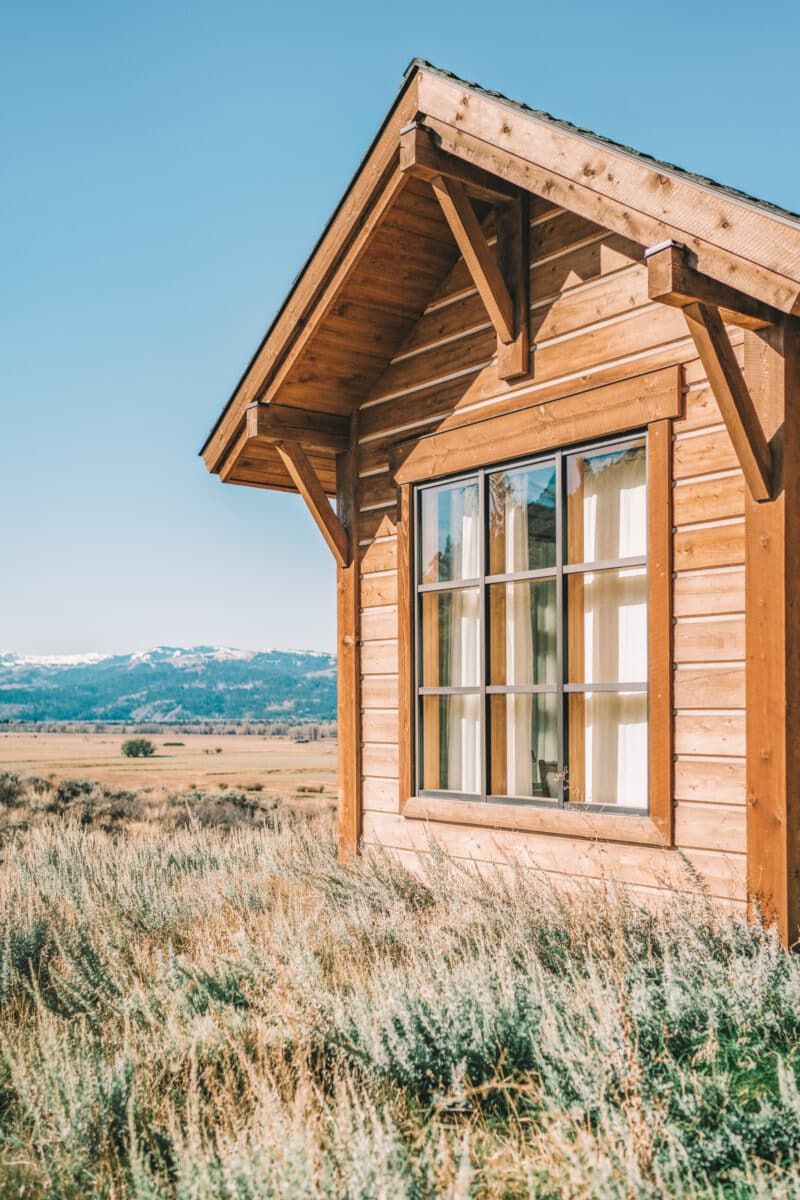 An example of a vacation rental like you might find on one of the best Airbnb alternative websites: a log cabin in a prairie landscape with snowy mountains in the background.