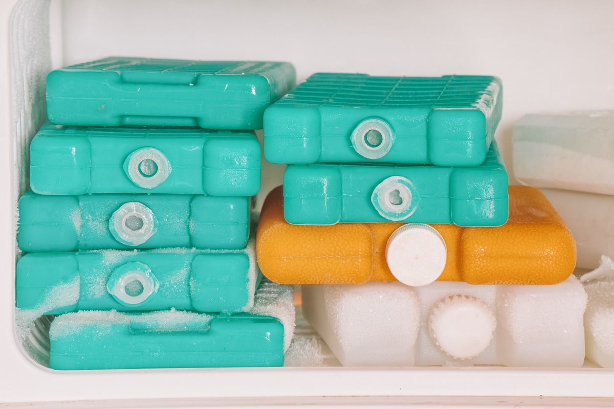 A freezer full of stacked turquoise, orange, and white plastic ice packs.