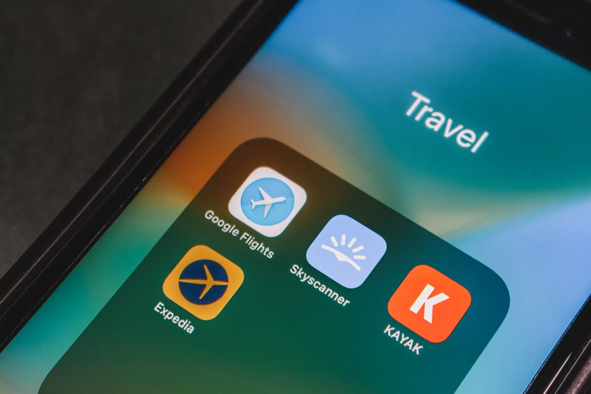 A close-up of an iphone screen showing the app icons for Google Flights, Scyscanner, Kayak, and Expedia.