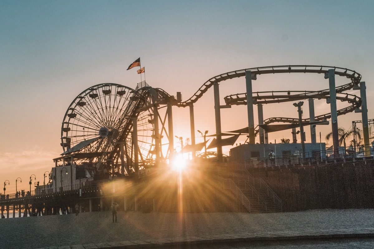 Silhouette of amusement park rides at the Santa Monica Pier, with the sun setting behind it.