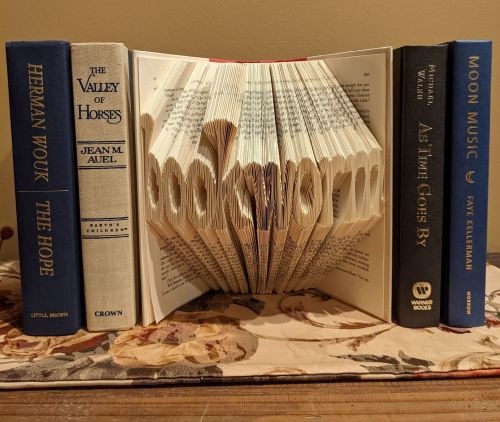 A book open to the camera with the pages carved to read "Bookworm."