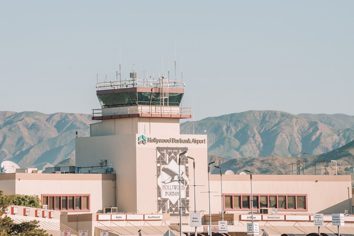 Hollywood Burbank Airport (BUR) seen from the outside with rolling hills and a hazy blue sky behind it.