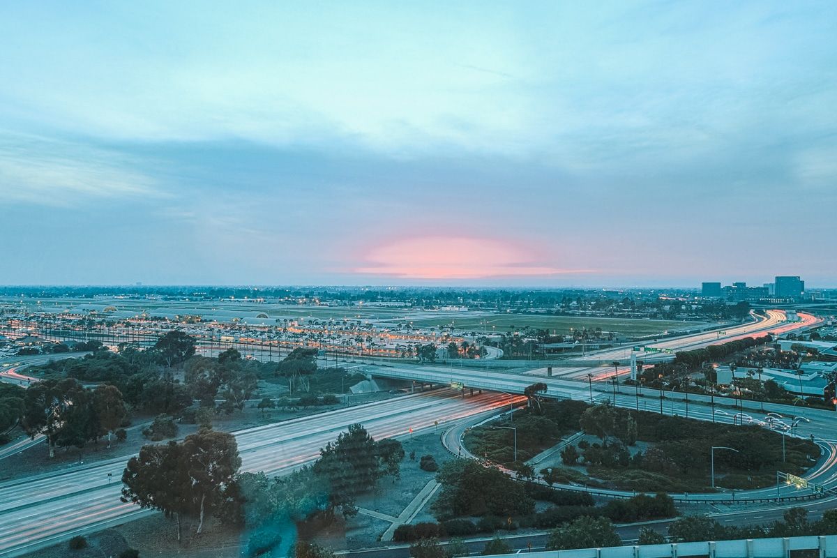 A view of the highways around John Wayne Airport seen from above, with a pinkish-blue sunset fading in the sky above.