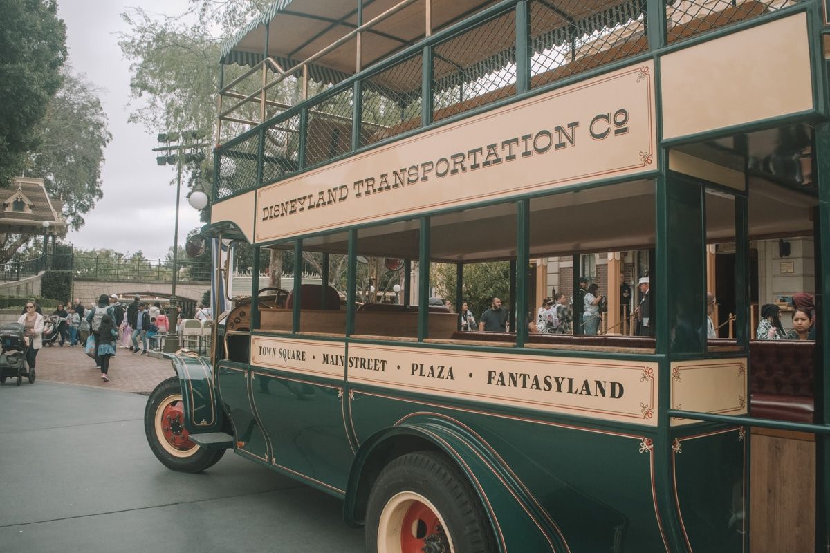 A dark green, old-timey, double-decker bus with the words, "Disneyland Transportation Co" written across the side.