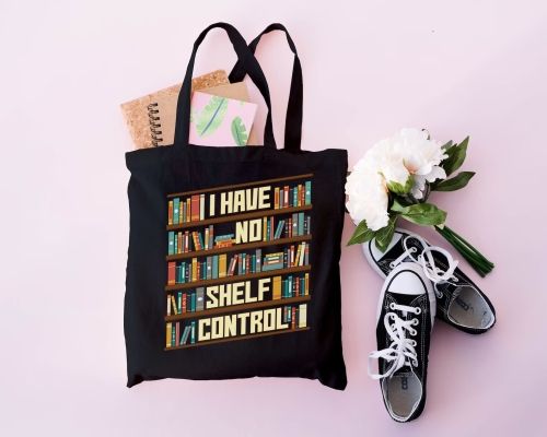 Black tote bag printed with a bookshelf that reads "I Have No Shelf Control Tote Bag" among the books. It's displayed with a pair of black and white converse, a bouquet of fake flowers, and journals.