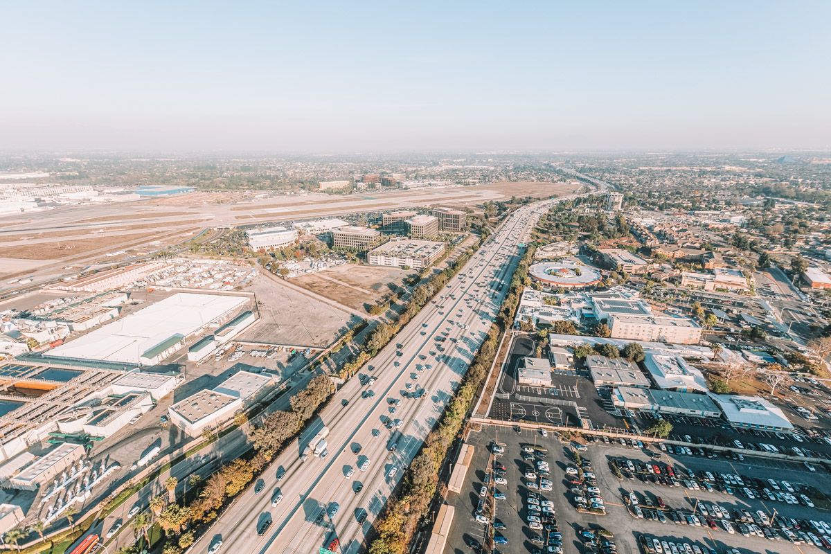 Aerial view of Long Beach Airport (LGB) on a semi-clear day, with cars driving on the freeway leading to it.