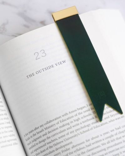 A green bookmark with golden topper sitting in a book opened two chapter 23 "The Outside View"