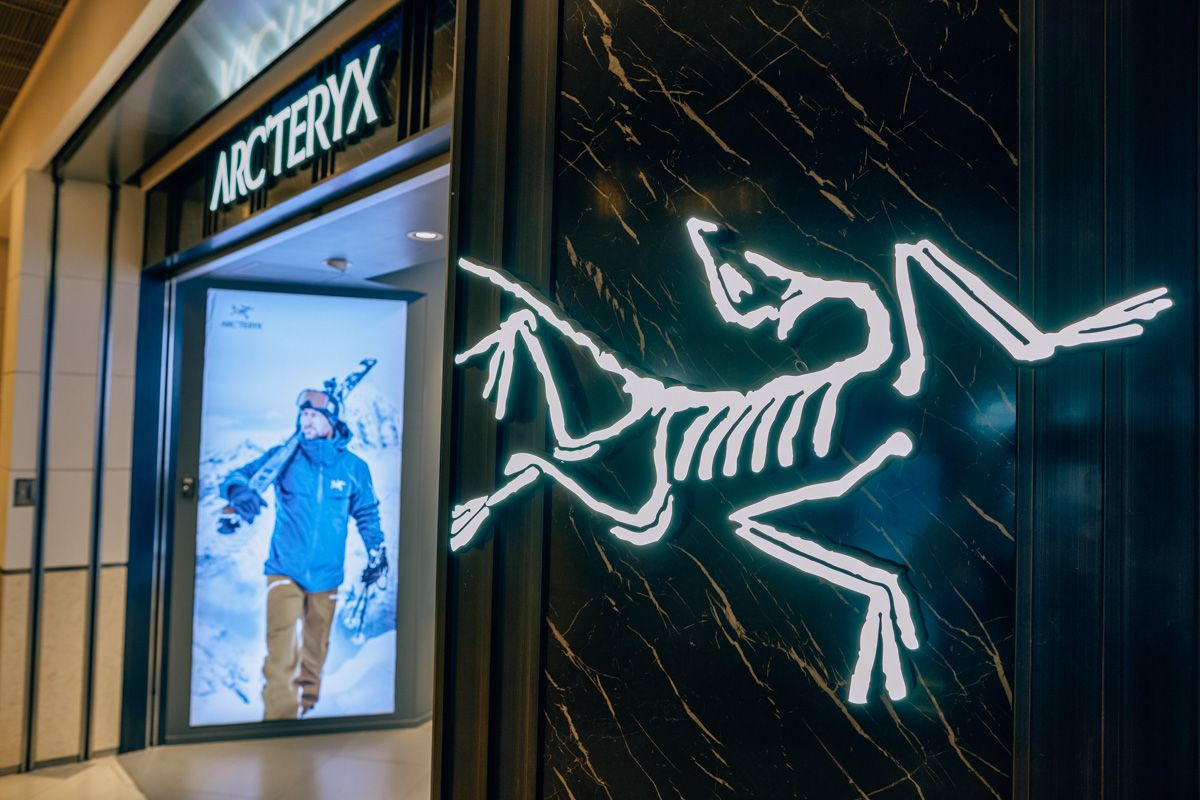 An Arc'teryx logo and sign on the  entrance to the storefront in a mall.