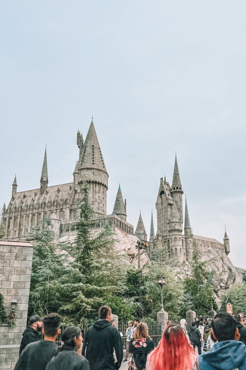 Closest Airports to Universal Studios Hollywood: A crowd looks up at the Hogwarts Castle replica at Universal Studios against an overcast sky.